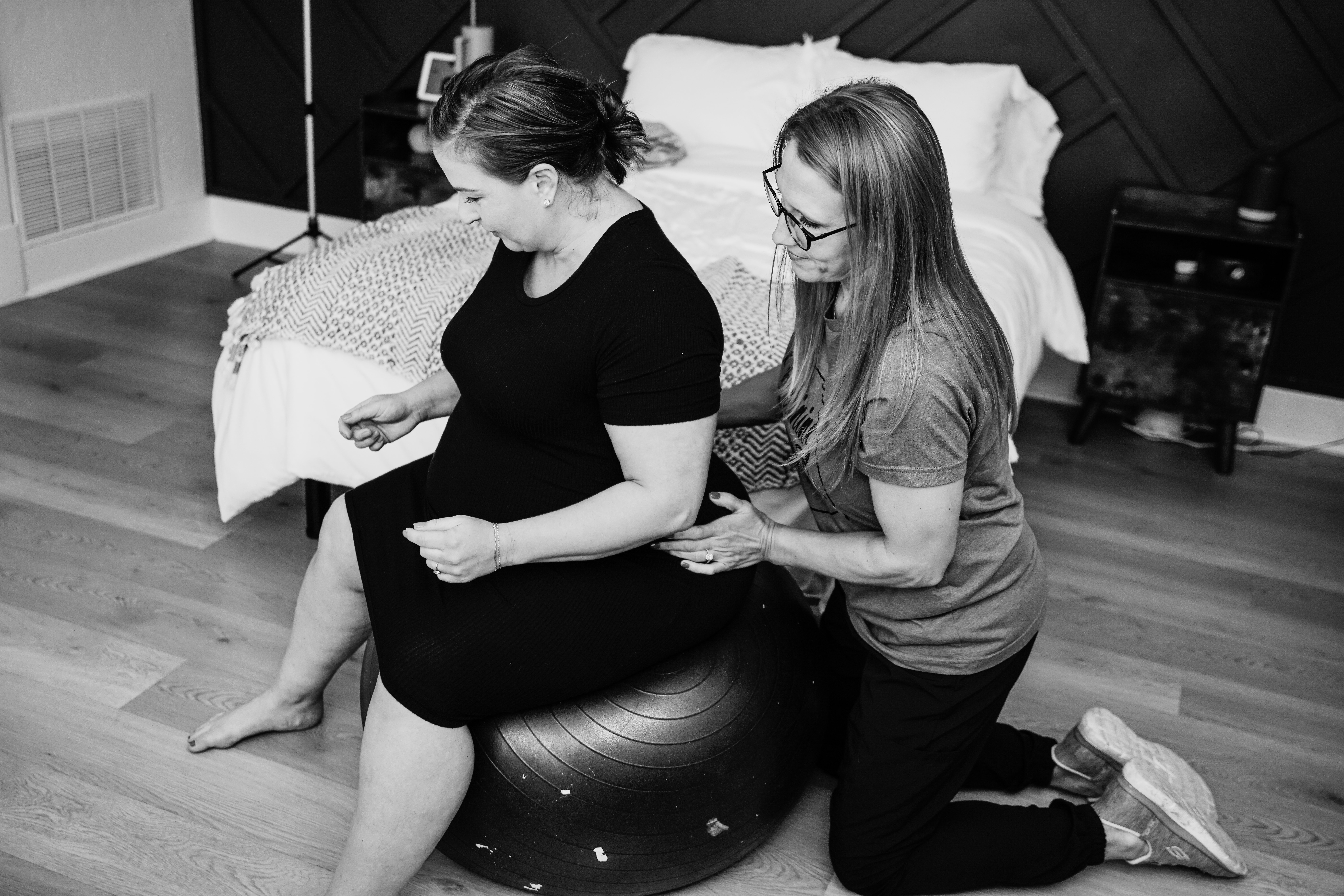 Doula providing hands-on support to a laboring woman in a birthing suite